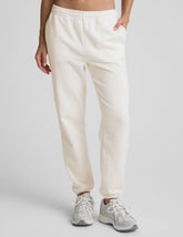 woman wearing white fleece sweatpants against a plain background.